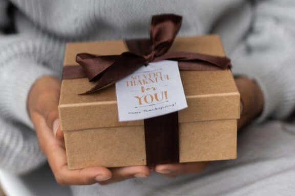 hands holding brown box with brown bow