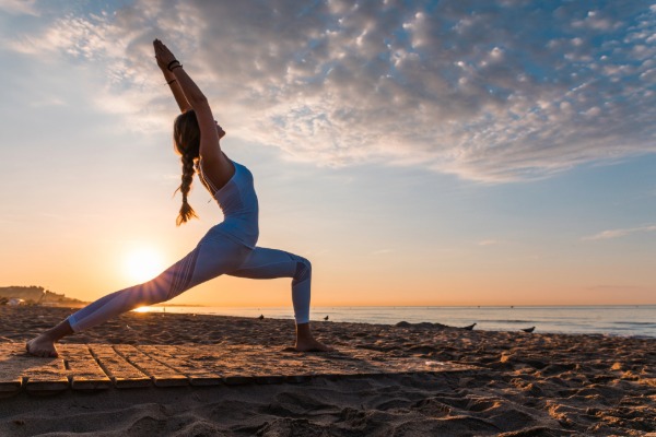woman on the beach practicing yoga at sunset near san clemente